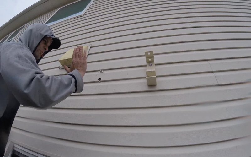 Competitor awning brackets bolted directly through vinyl siding with no ledger board