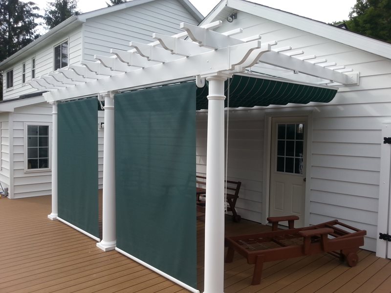 Solar shade panels on white pergola with green fabric